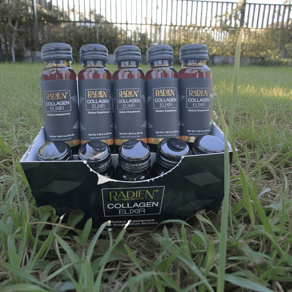 Pack of Radien Collagen Elixir bottles on grass, a dietary supplement with collagen for healthy skin.